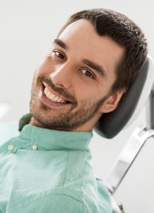 A closeup of a smiling man sitting in a dentist’s chair