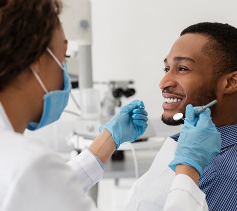 A smiling man receiving care from his dentist