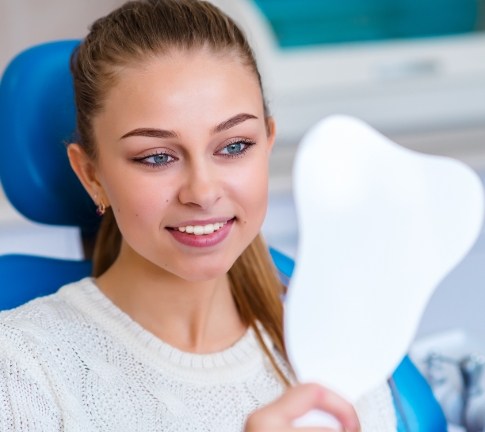 Woman looking at her smile after makeover