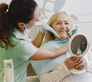 Dentures patient in Raleigh smiling in the mirror