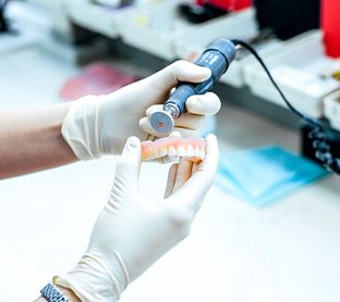 a dental lab technician buffing a newly created denture