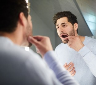 Man with lost filling looking at smile in mirror