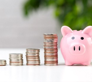 Coins next to piggy bank for cost of dentures in Raleigh