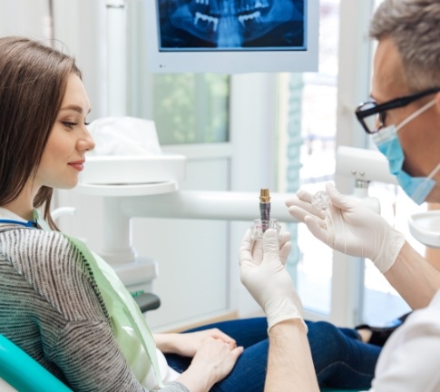 Dentist showing patient a dental implant model