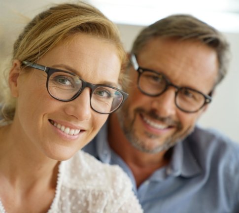 Man and woman sharing perfected smiles after dental implant tooth replacement