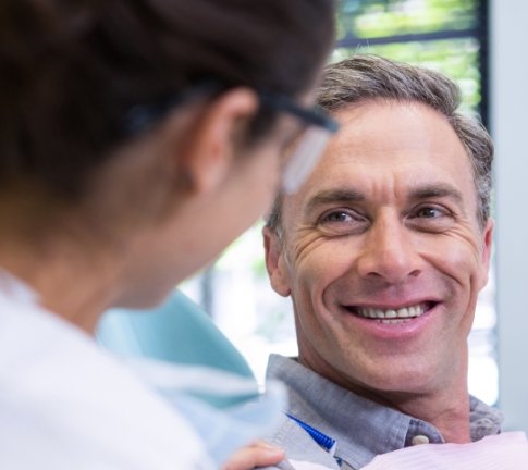 Man smiling at dentist after dental implant tooth replacement