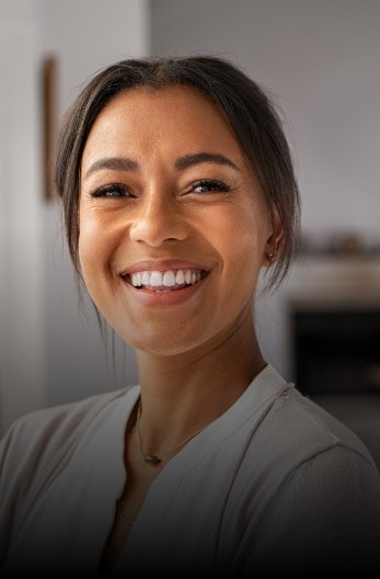 Smiling woman wearing gray cardigan indoors