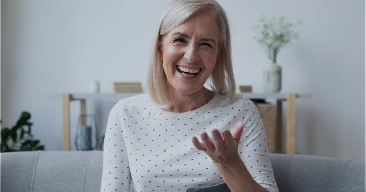 Senior woman laughing while sitting on couch