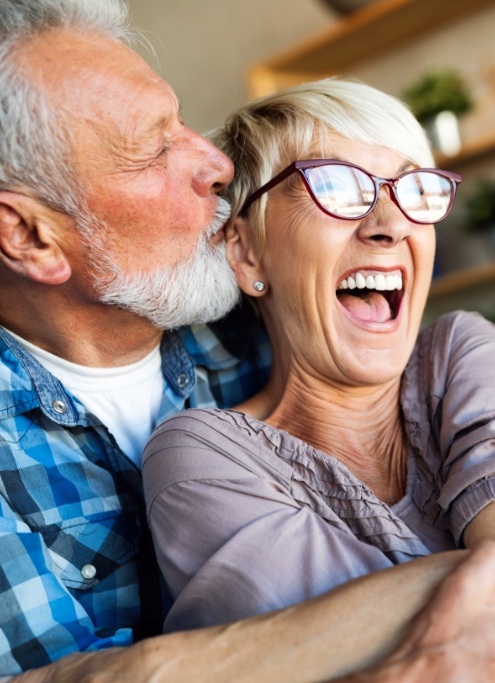 Happy man and woman smiling after replacing missing teeth