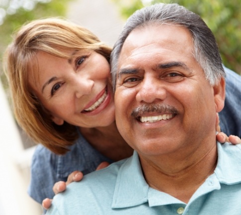 Man and woman sharing perfected smiles after full mouth reconstruction