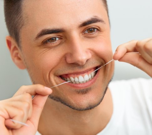 Patient flossing teeth during daily at-home oral care routine