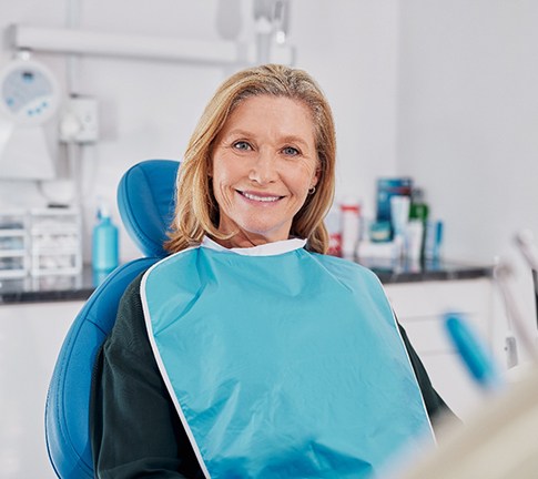 Mature woman sitting in dental chair and smiling
