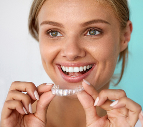 Woman smiling while holding whitening tray