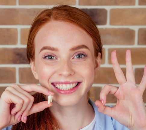 Woman holding up wisdom tooth after extraction