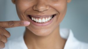 a woman pointing to her new smile after a cosmetic dental treatment