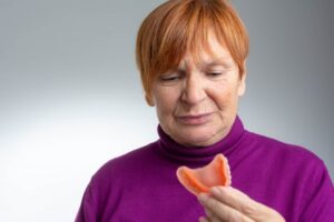 Woman holding her denture that smells bad